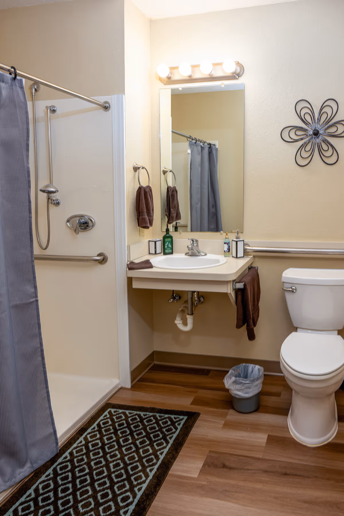 Bathroom with a walk-in shower, sink under a mirror, toilet, and towels on racks.
