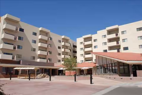Exterior view of a multi-story senior living complex with a central courtyard and shaded walkways.