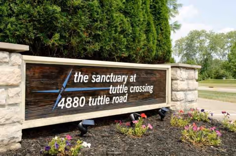 Exterior sign for Sanctuary at Tuttle Crossing with stone pillars and flowers.