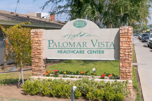 Stone-framed sign reading "Palomar Vista Healthcare Center" with the number 201 above, set in a landscaped front yard.