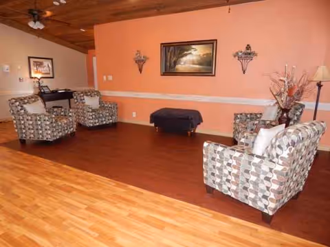 Spacious living room with patterned armchairs, artwork, and a small ottoman.