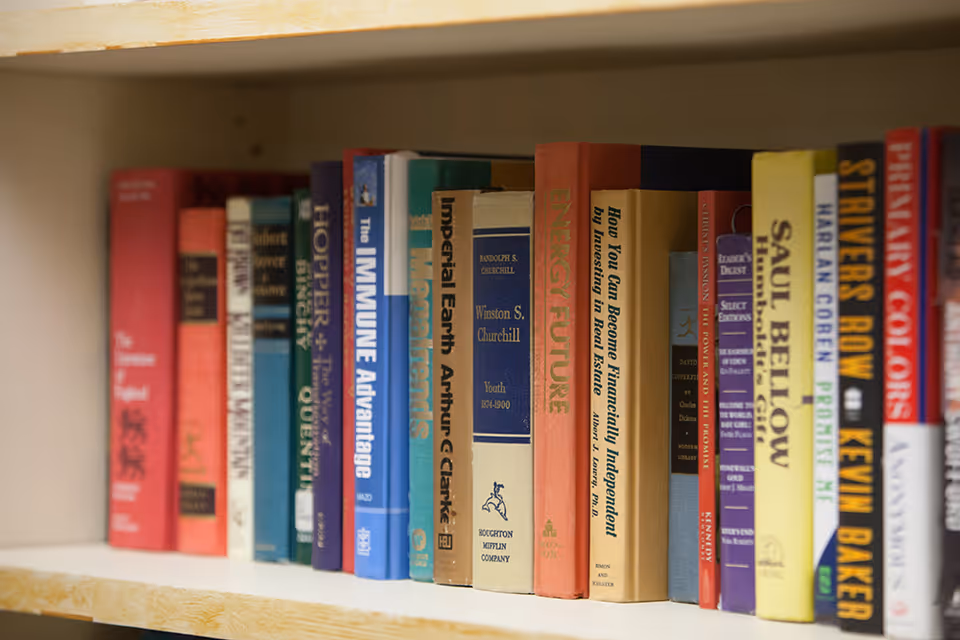 A close-up view of a bookshelf filled with various books of different colors and sizes, neatly arranged side by side.