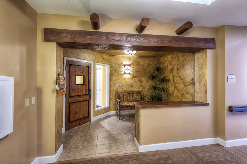 A warm interior entry alcove with a wooden door, bench, decorative wood beams and textured walls.