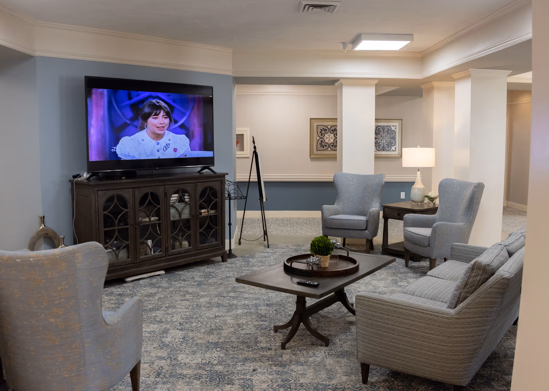 Comfortable common living room with a TV on a cabinet, armchairs, a sofa, and a coffee table.