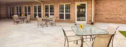 Outdoor patio with metal tables and chairs in front of a brick building.