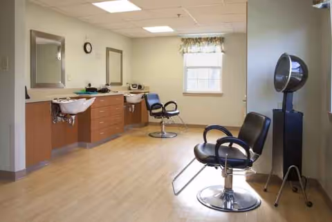 A senior living facility hair salon with mirrors, sinks, and styling chairs.