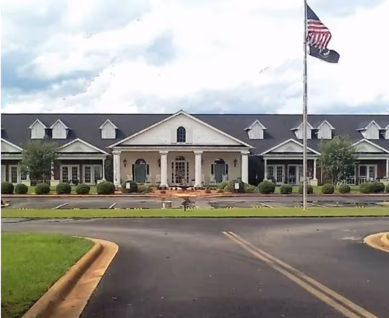 Front view of Sumter County Retirement Village, a single-story building with a flagpole.