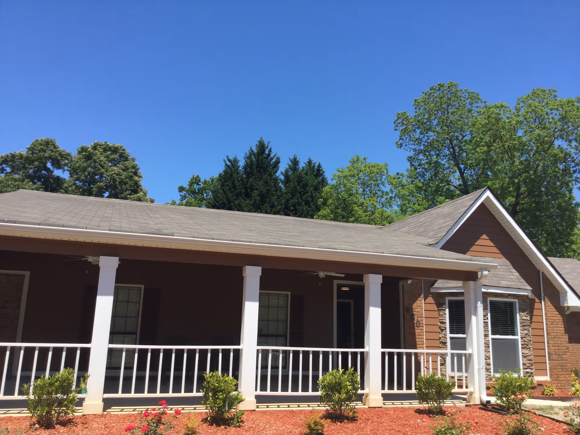 Front exterior of a single-story residential building with a covered porch, white columns, and landscaped beds.