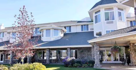 Exterior view of Stone Lodge Gracious Retirement Living with stone columns and landscaped entrance