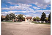 Front view of Garden Terrace at Aurora facility with driveway, trees, and clear sky.