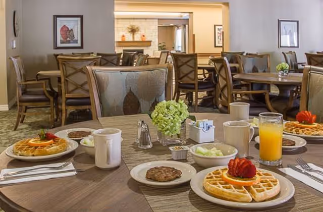 Dining room with tables and chairs set for breakfast, showing plates of waffles, coffee, juice and table decor.