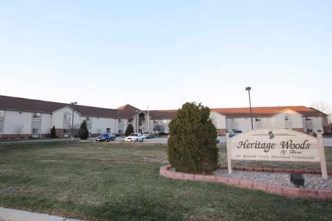 Exterior view of Heritage Woods of Flora with a sign, building, and cars.