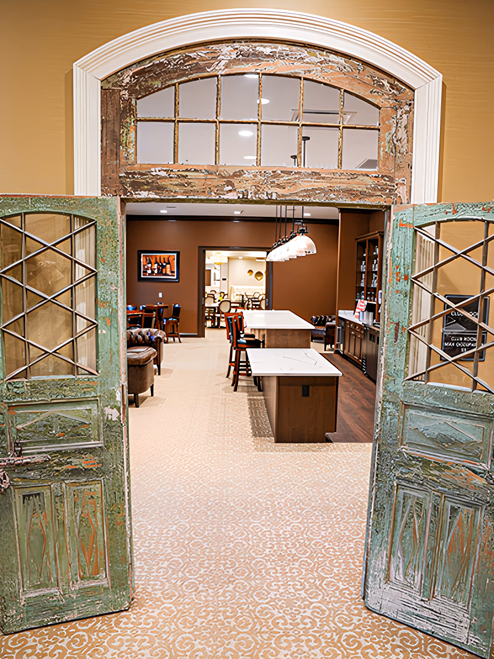 Open distressed double doors leading into a communal dining and seating area with tables, chairs and pendant lights.