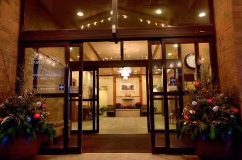 Glass doors open into a warmly lit lobby with brick walls and potted plants.