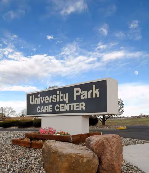 Outdoor view of University Park Care Center sign with rocks and landscaping.