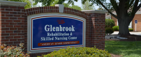 Brick sign reading Glenbrook Rehabilitation & Skilled Nursing Center before landscaped grounds.