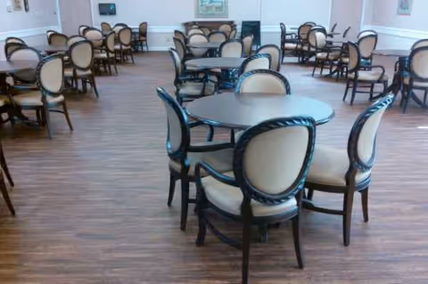 Calera Manor dining hall with round tables and cushioned chairs.