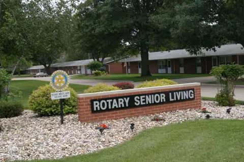 Exterior view of Rotary Senior Living entrance with a brick sign and landscaping.