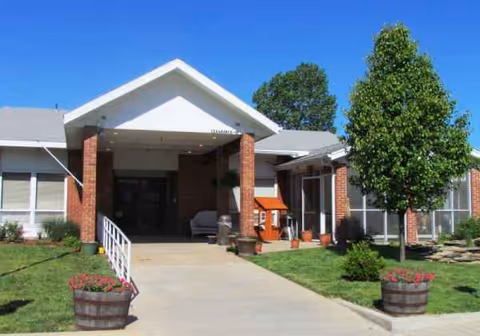 Front exterior view of Medicalodges Columbus entrance with brick columns and trees.