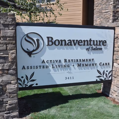 Outdoor sign for Bonaventure of Salem, an active retirement, assisted living, and memory care facility, mounted between two stone pillars with grass and part of a building visible in the background.