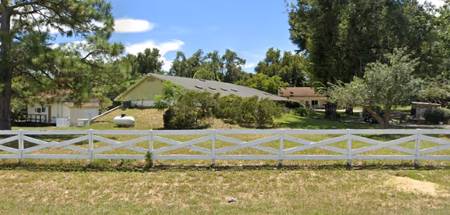 Exterior view of Elders of Mount Dora facility with white fence and trees.