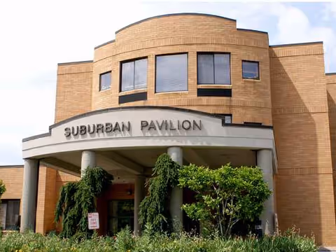 Brick healthcare facility entrance with pillars and greenery, labeled Suburban Pavilion.