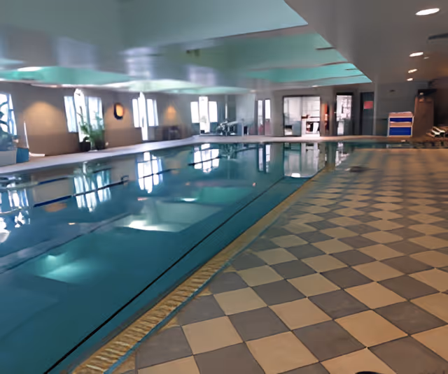 Indoor swimming pool with lane markings and a checkered tile deck in a well-lit recreation room.
