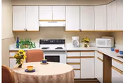 Cozy kitchen with white cabinets, small round table, and appliances.