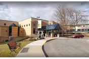 Exterior view of The Inn at Menorah Park facility with entrance canopy, parking, and benches.