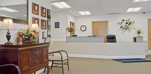 Reception area of a senior living facility with a front desk and seating.
