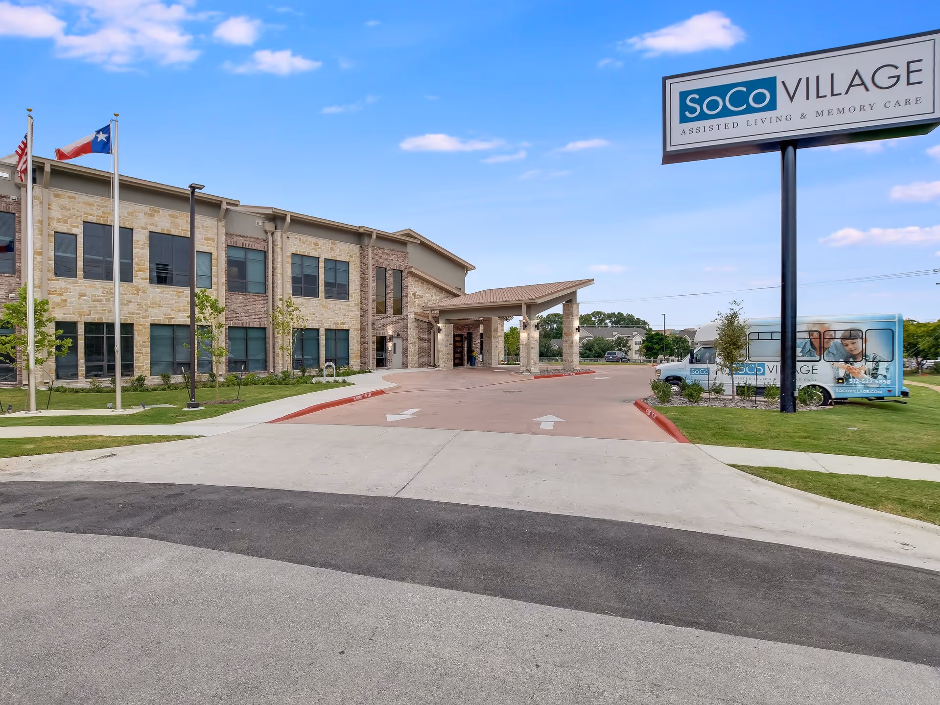 Front entrance of SoCo Village assisted living building with driveway, sign, and shuttle van.