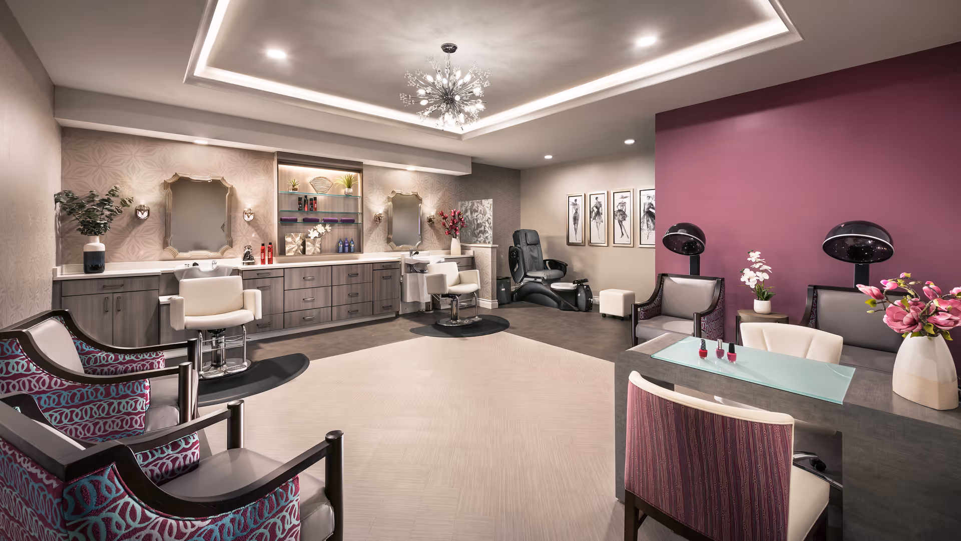 Well-lit, upscale salon-style interior with styling chairs, manicure table, hair dryers, and relaxation seating.