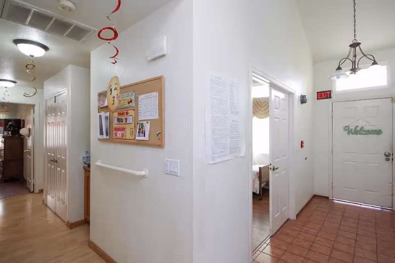 A bright hallway with bulletin board, doors, and a Welcome door in a senior living facility.