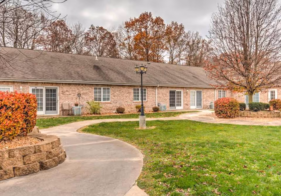 Front view of Brookstone Estates of Paris showing brick building, curved path, lawn, trees