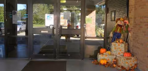 Entrance lobby of Allen Oaks Nursing & Rehab Center featuring pumpkins and scarecrows by the doors.