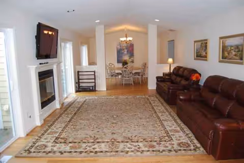 Bright living room with leather sofas, a fireplace, and a dining area in the background.