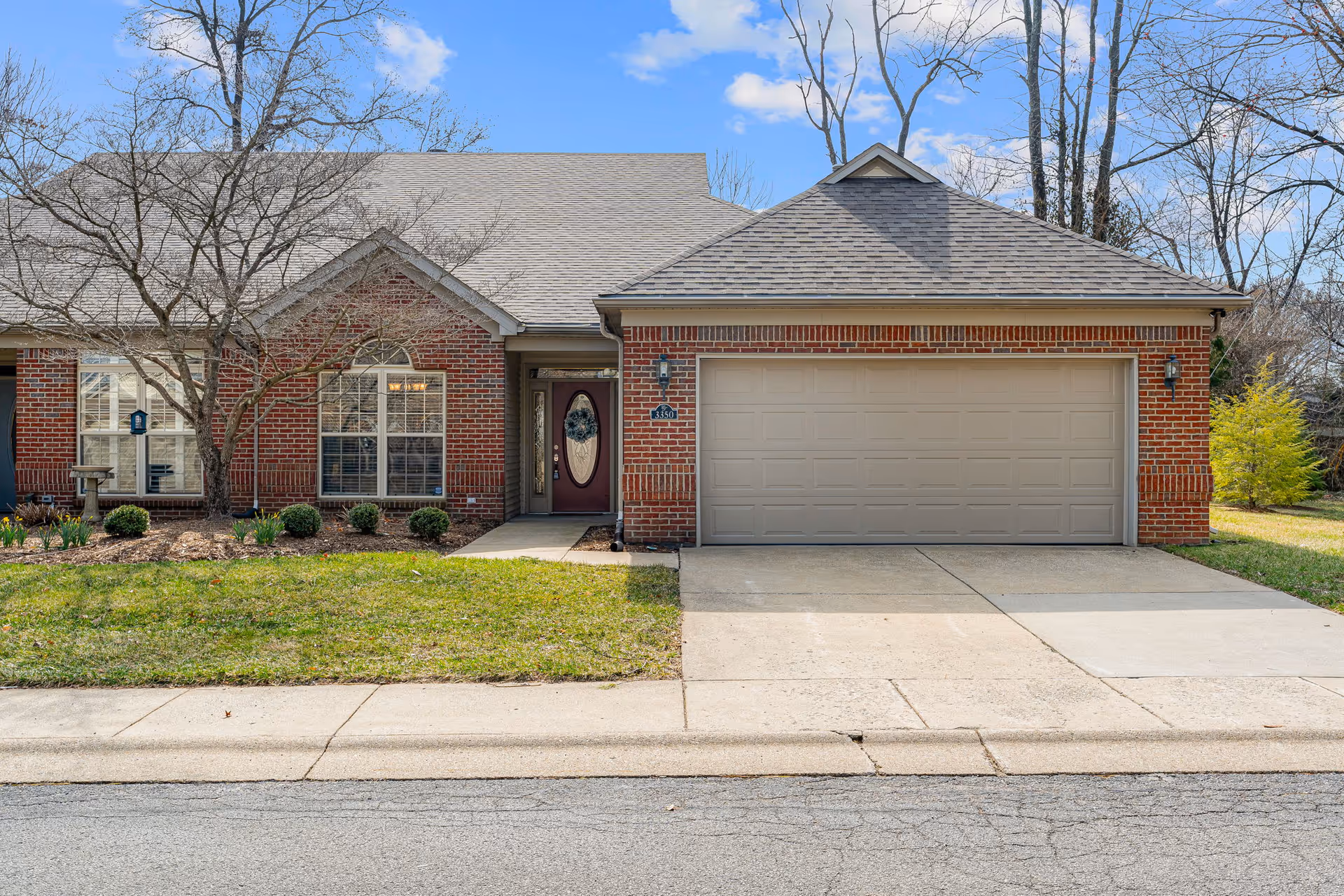 Single-story brick building front with a two-car garage, central entry door, large windows, and a small front lawn.