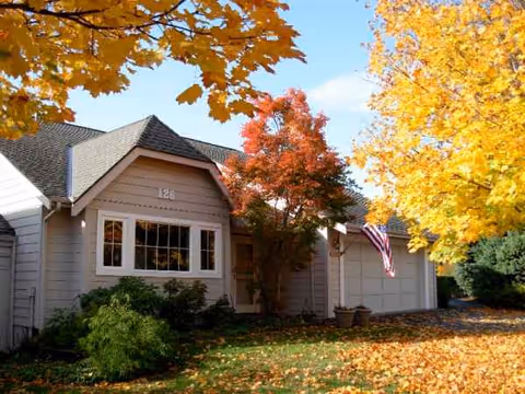 Front view of Providence Point facility with autumn leaves, trees, and an American flag.