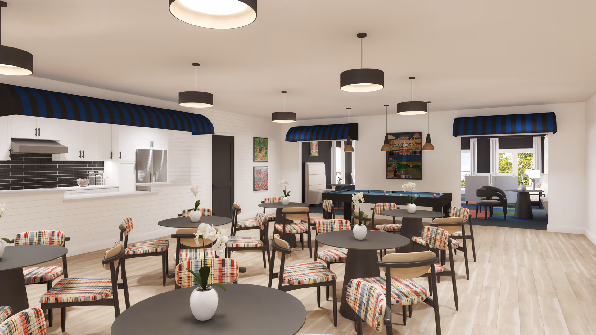Bright communal dining and activity room with round tables and colorful upholstered chairs, a service kitchen pass-through, and a pool table in the back.