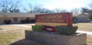 Exterior view of Oak Manor Nursing Home entrance sign with a low brick planter