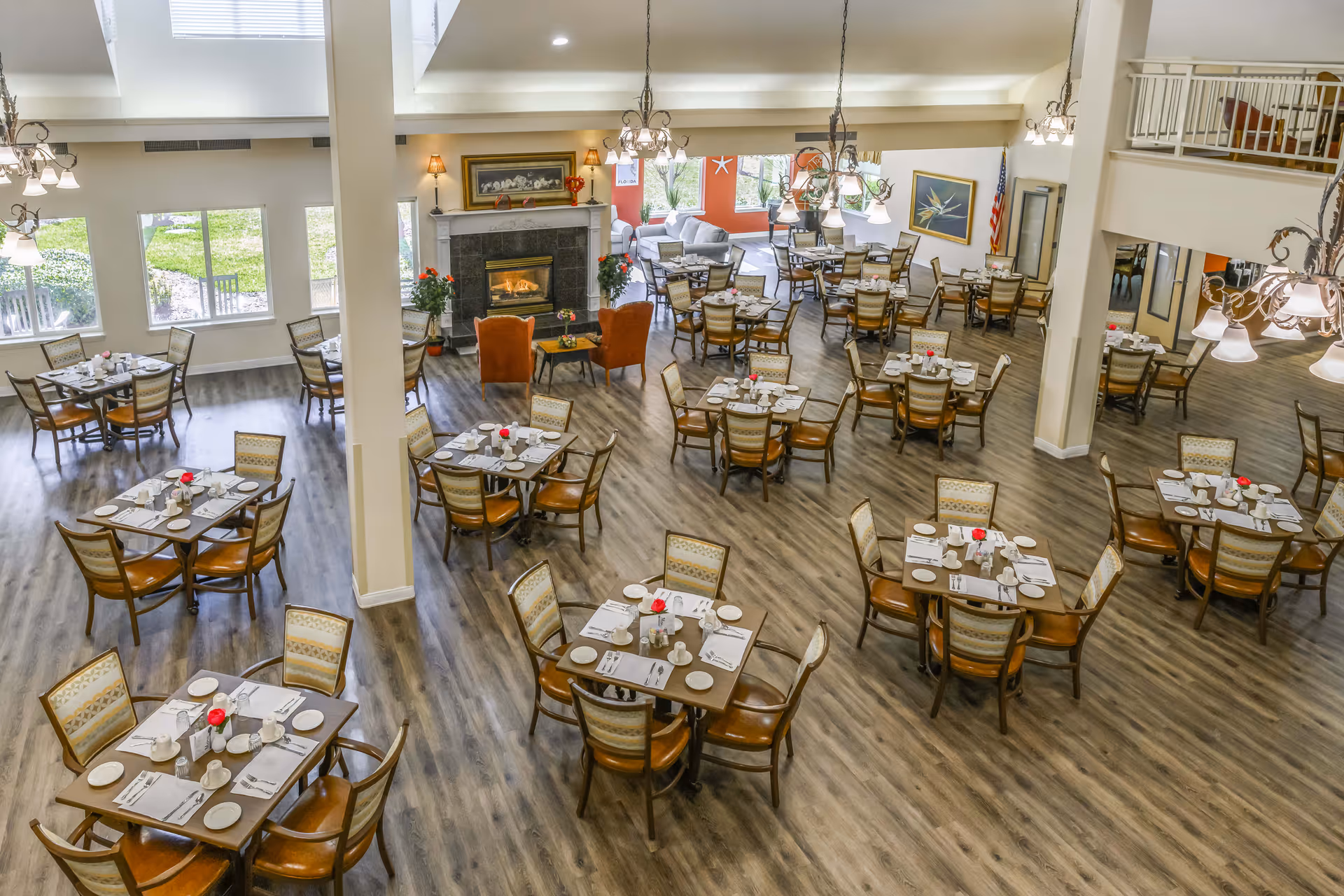 Spacious dining room with multiple set tables and chairs, a fireplace, and large windows.