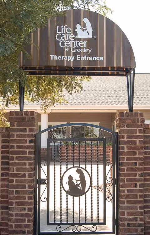 Life Care Center of Greeley therapy entrance sign atop brick gate