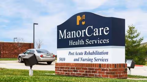 A ManorCare Health Services sign on a brick base in a grassy outdoor area.
