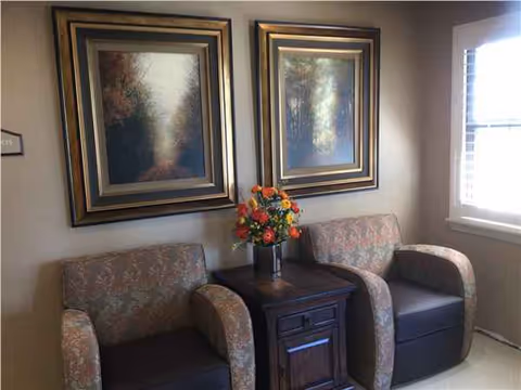 Two patterned chairs flank a small wooden table with a vase of flowers.
