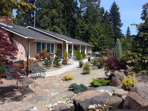 Single-story senior living facility exterior with landscaped garden, rock features, and patio seating.