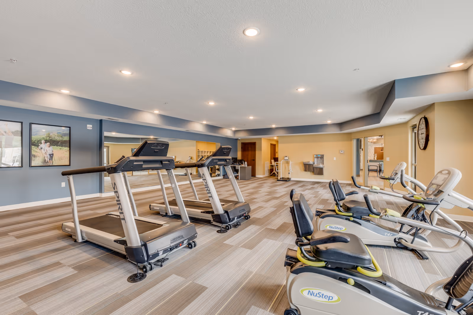 Bright, spacious fitness room with treadmills and NuStep recumbent exercise machines.