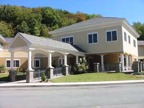 Exterior view of a beige two-story rehab facility with a covered entrance and lawn