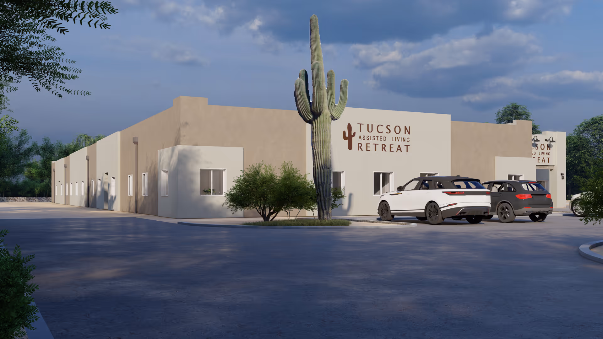 Low-rise stucco assisted living building with a large saguaro cactus and two cars parked in front under a cloudy sky.