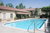 Outdoor pool area with beige buildings and surrounding lounge chairs.