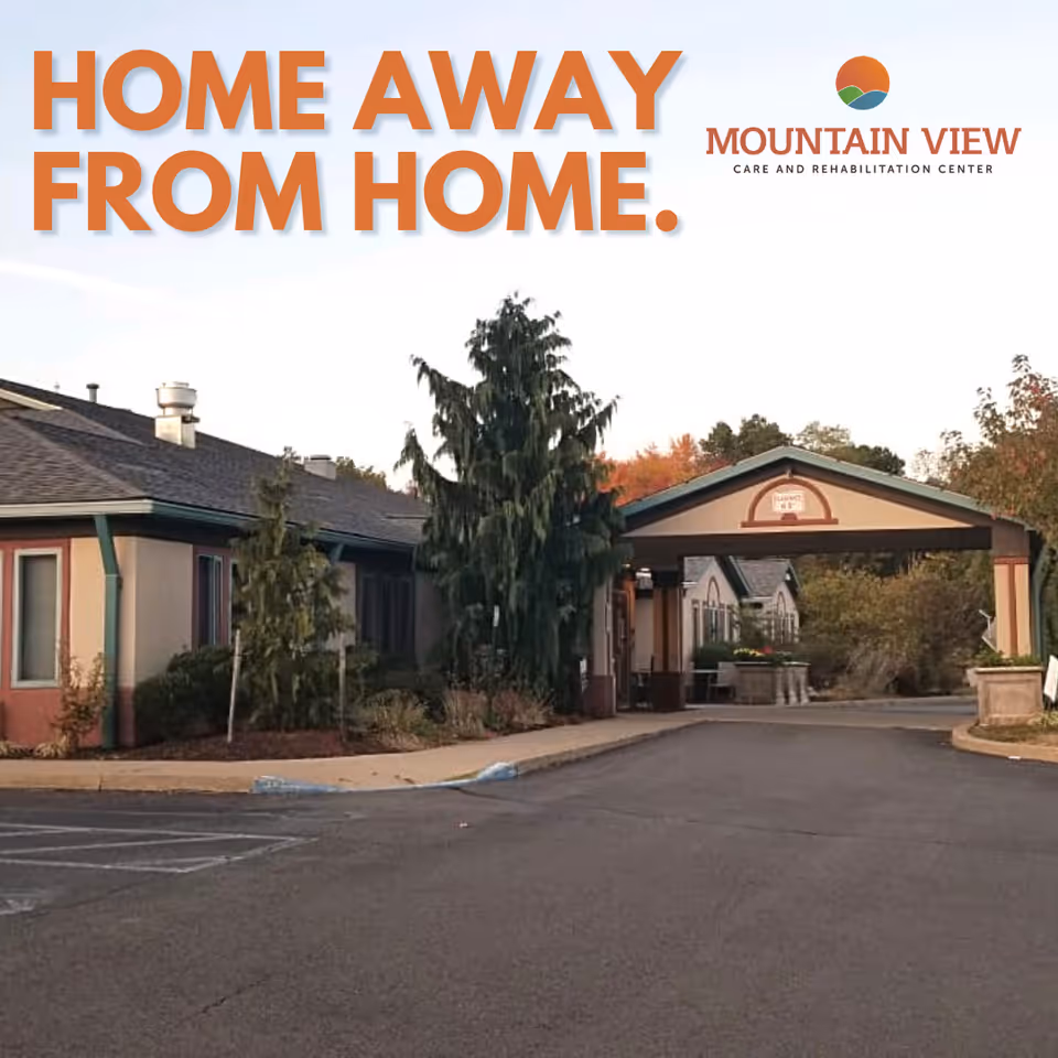 Exterior view of Mountain View Care and Rehabilitation Center showing the building entrance with a covered driveway, surrounded by trees and landscaping under a clear sky.